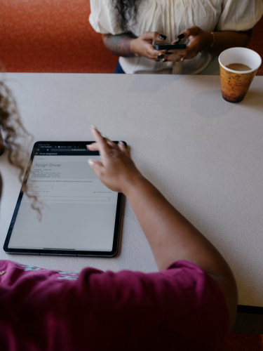 Carrier sitting in a diner assigning a driver to Amazon Relay load using an ipad
