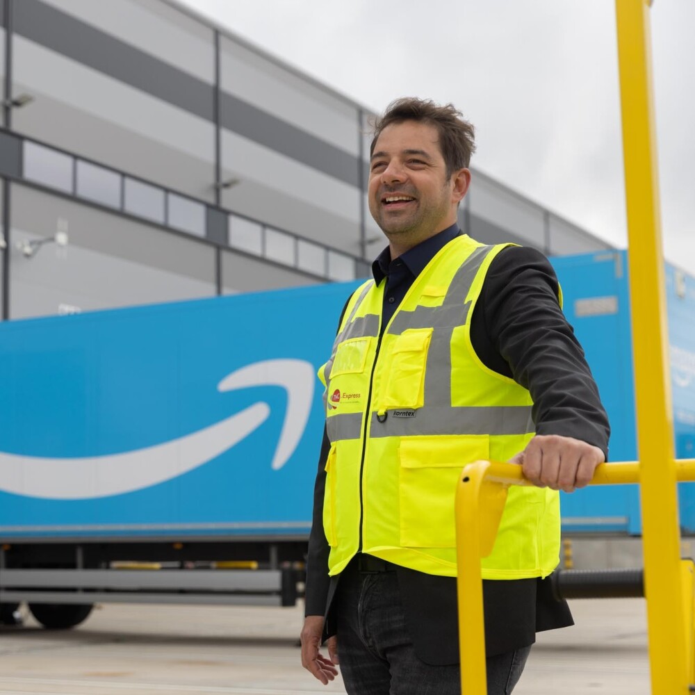man standing in amazon yard next to prime trailer.jpg