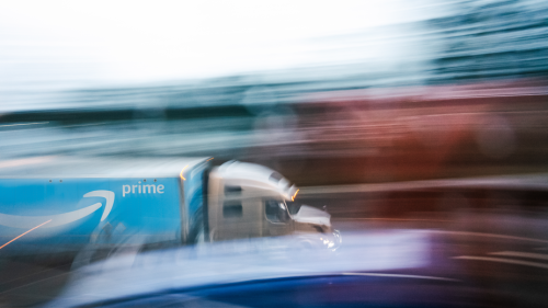 blurred image of a semi hauling an amazon prime trailer on a busy highway