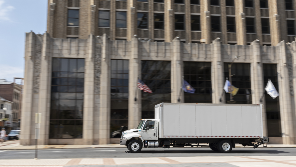 box truck driving past a government building.png